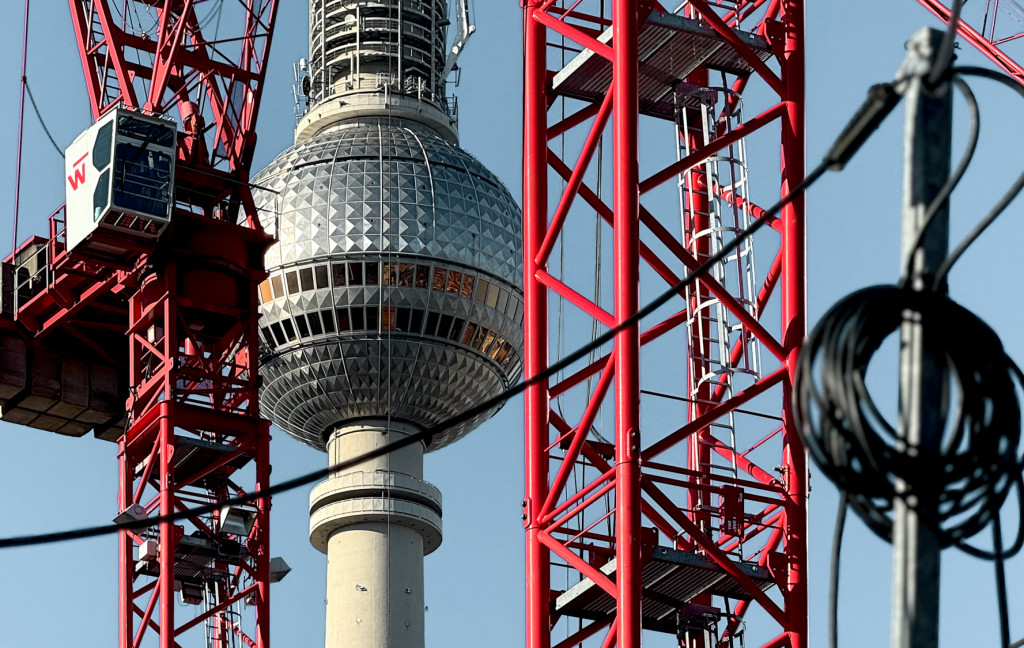 Rote Baukräne am Alexanderplatz mit blauem Himmel. Architekturführungen in Berlin