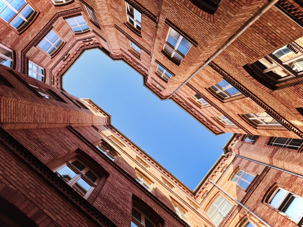 Looking up from the courtyard of a refurbished historical building in red brickwork to a blue sky