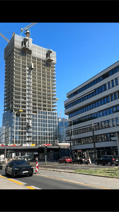 Shell construction of a Highrise building at Alexanderplatz in Berlin. Cars passing on a street in the foreground.